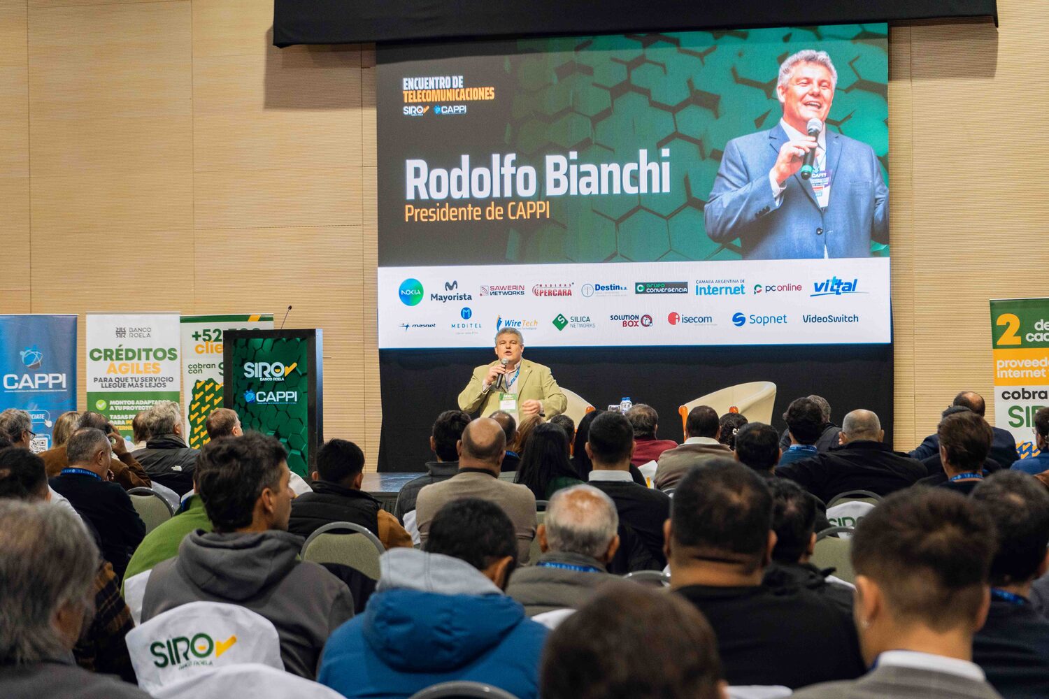 Disertante en escenario ante auditorio completo, edición 2025